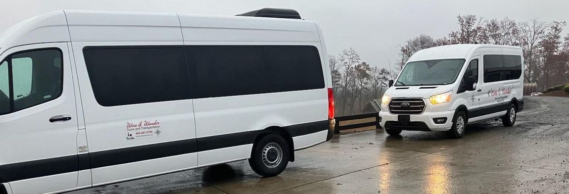 Two white vans are parked next to each other on a wet road.