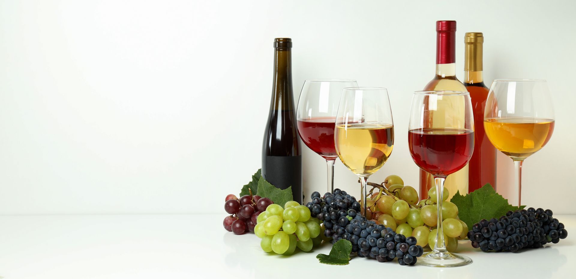 Bottles of wine , glasses of wine , grapes and leaves on a table.