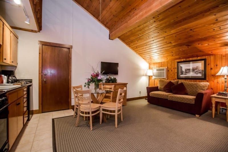 Cozy living space: Kitchen, dining table, and living area with couch, TV, and wood paneling.