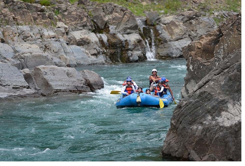 A group of people are rafting down a river near a waterfall