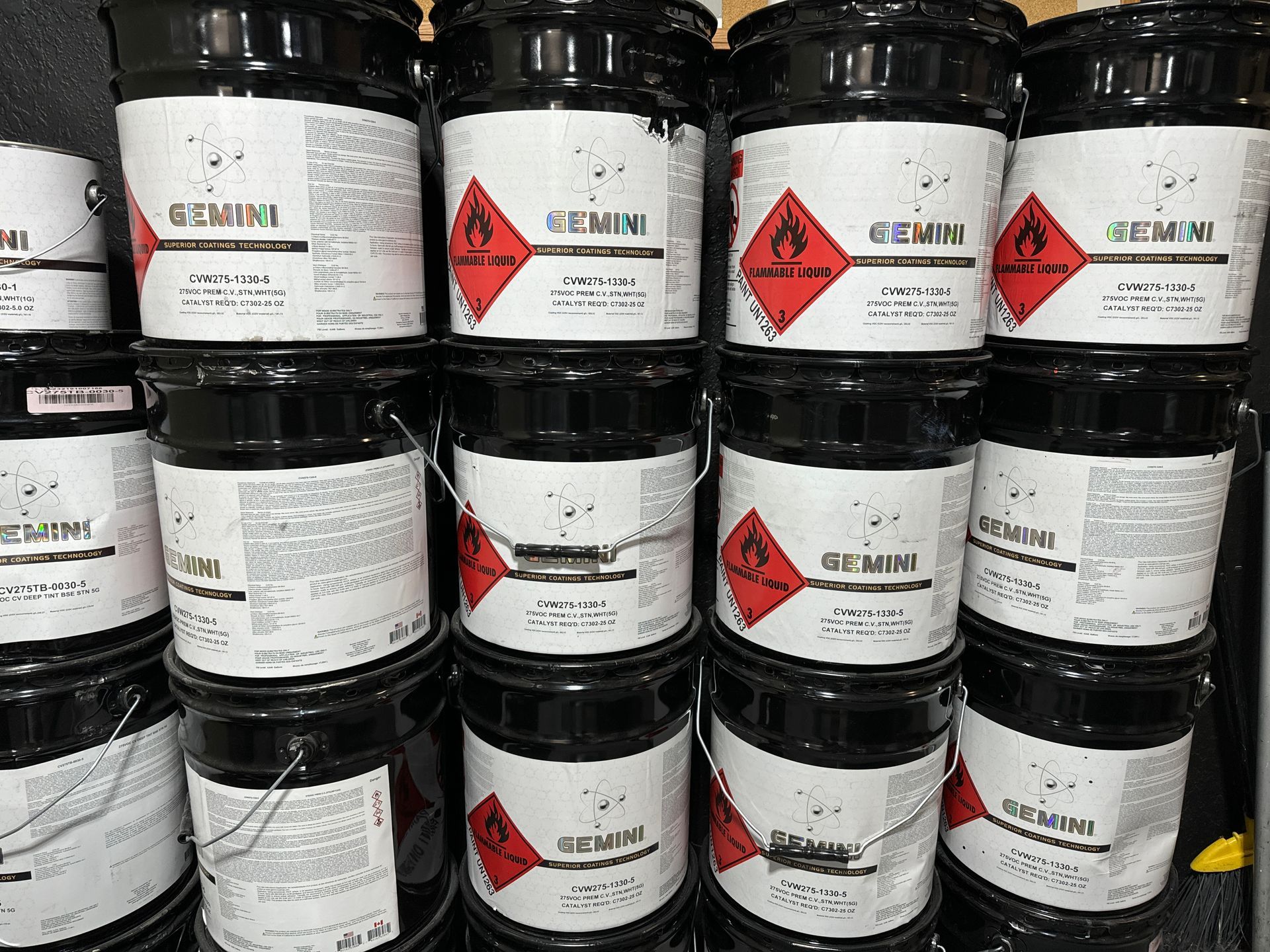 A bunch of buckets of chemicals are stacked on top of each other.