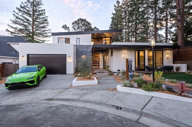 Modern two-story house with a lime green sports car in the driveway at dusk