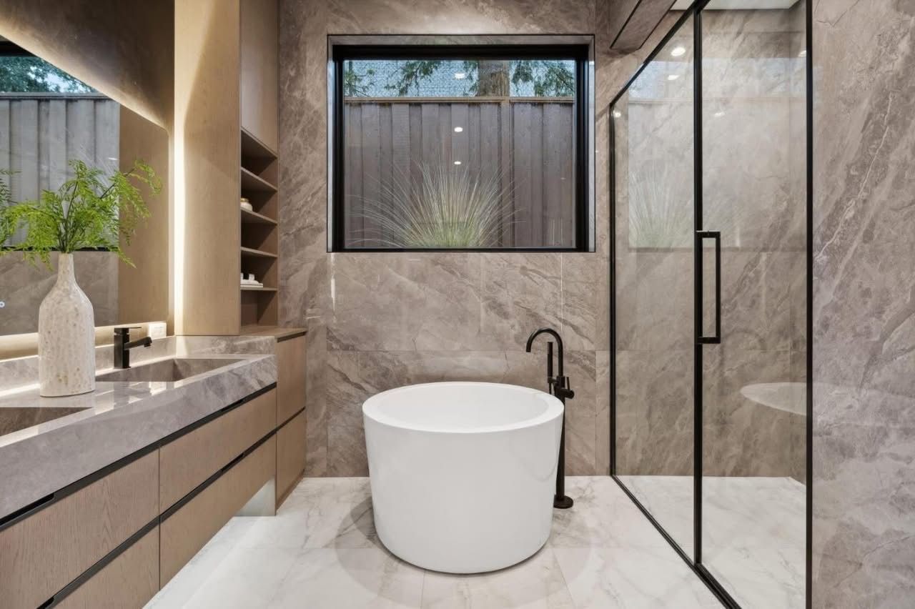 Modern marble bathroom with a freestanding tub, glass shower, and vanity sink.