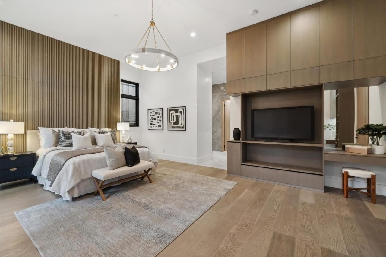 Modern bedroom with a bed, neutral decor, wood-paneled TV wall, and a large rug