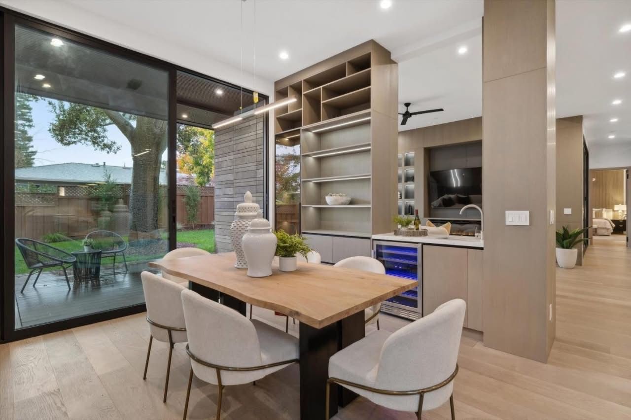 Modern kitchen and dining area with a wooden table, white chairs, and sliding glass doors to a patio.
