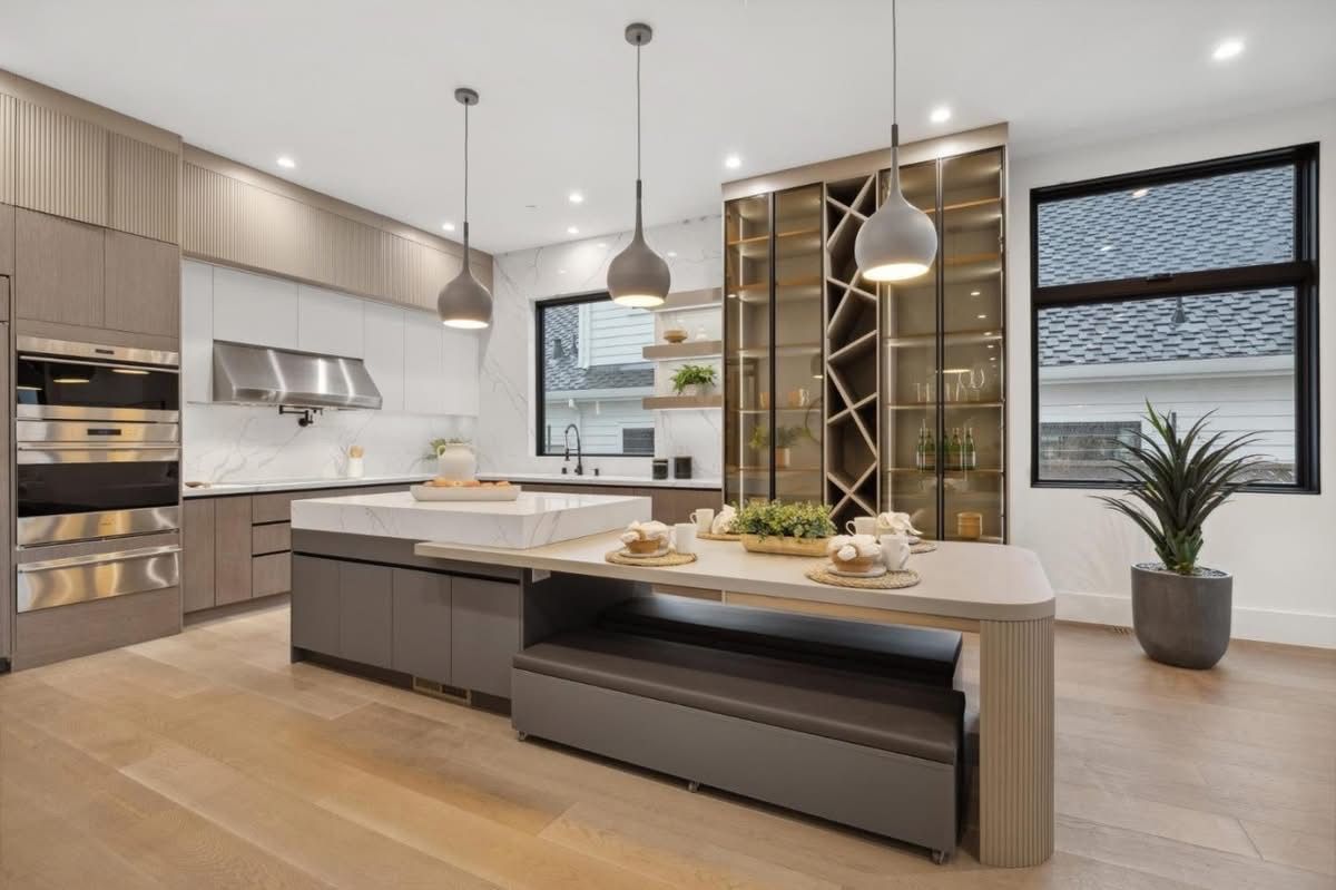Modern kitchen with island, pendant lights, built-in wine rack, and large windows.