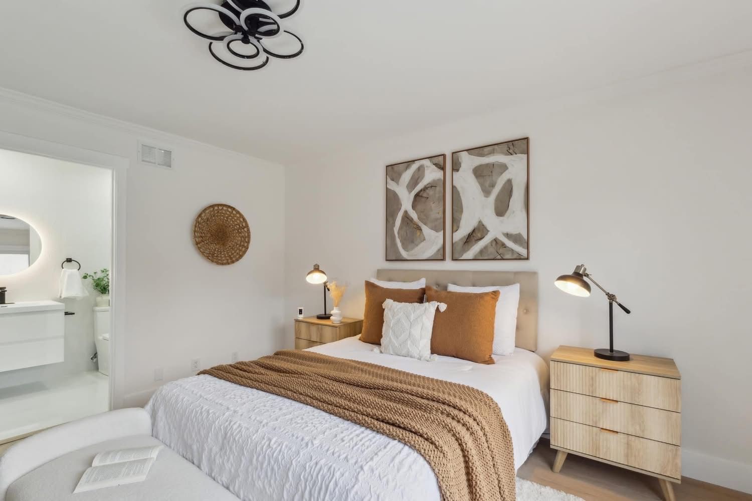 Bright bedroom with a white bed, mustard accents, bedside lamps, and wall art