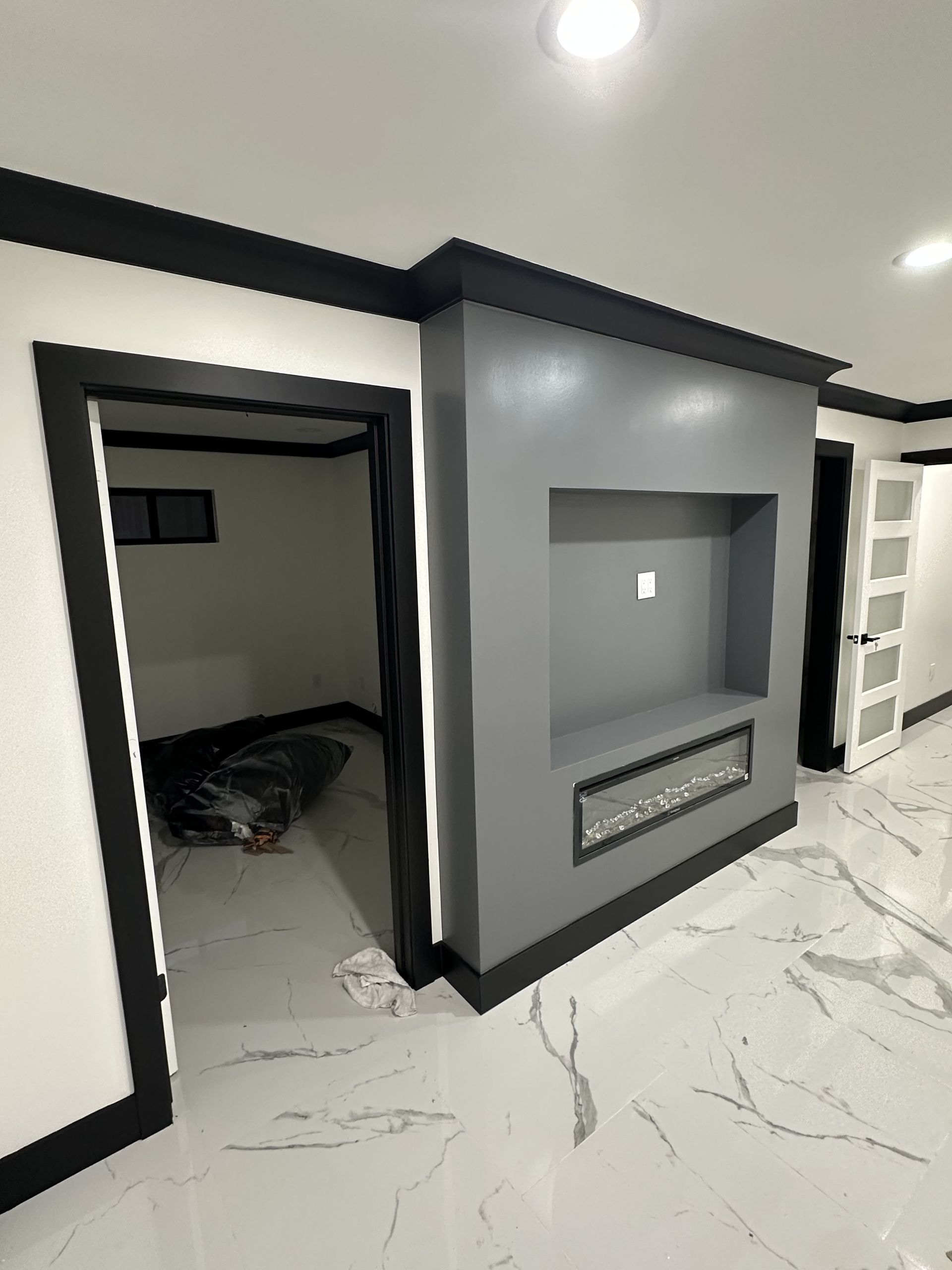 Modern interior hallway with gray accent wall, recessed niche, and marble-pattern tile floor.