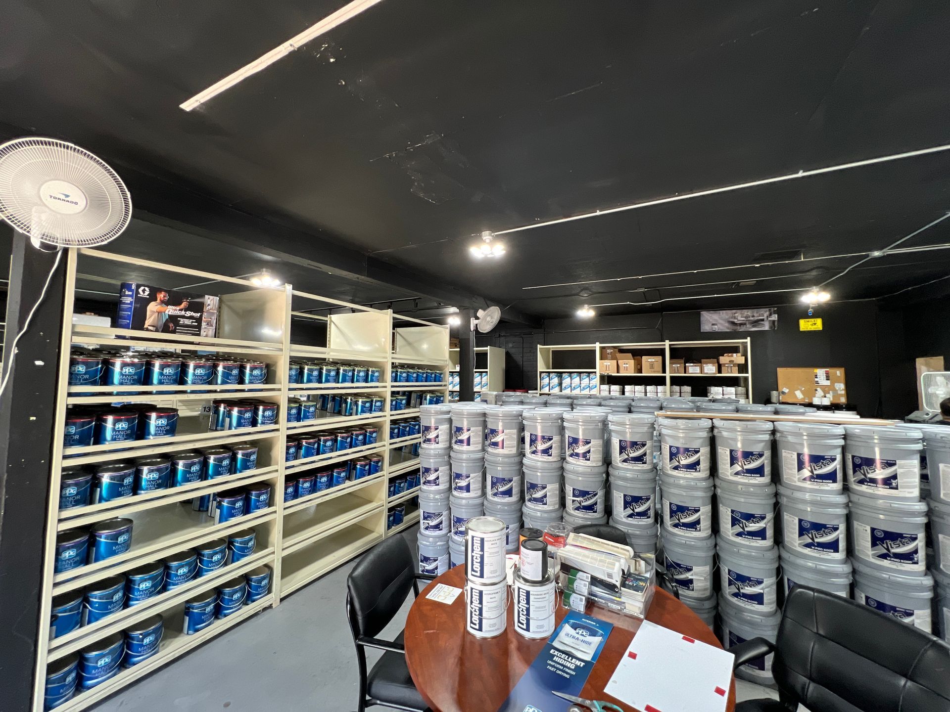 A room filled with lots of buckets of paint and a table.