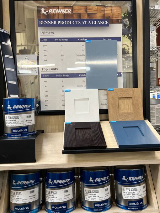 Stacked beige paint buckets with blue labels in a store aisle