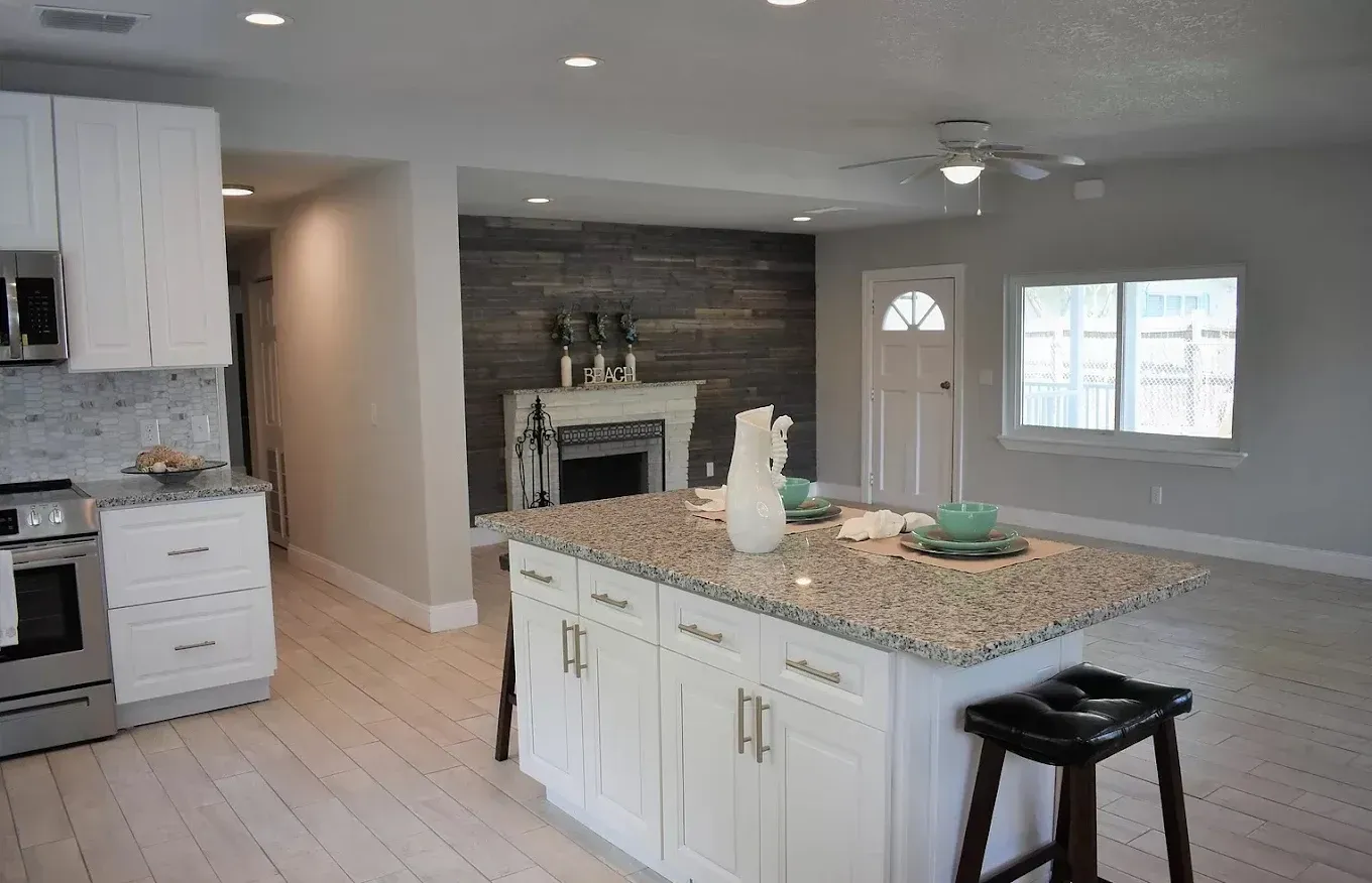 Modern kitchen with white cabinets, island, and fireplace.