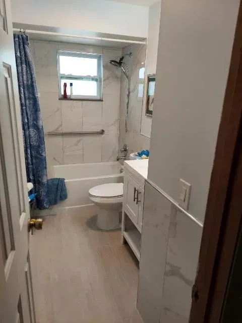 Bathroom with a white toilet, sink, and tub with a blue shower curtain.