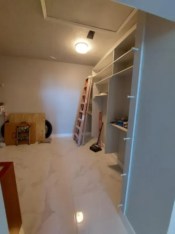 Interior room with white shelves, a wooden ladder, and a gray floor.