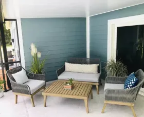 Outdoor patio with gray wicker furniture, blue walls, and a wooden coffee table.