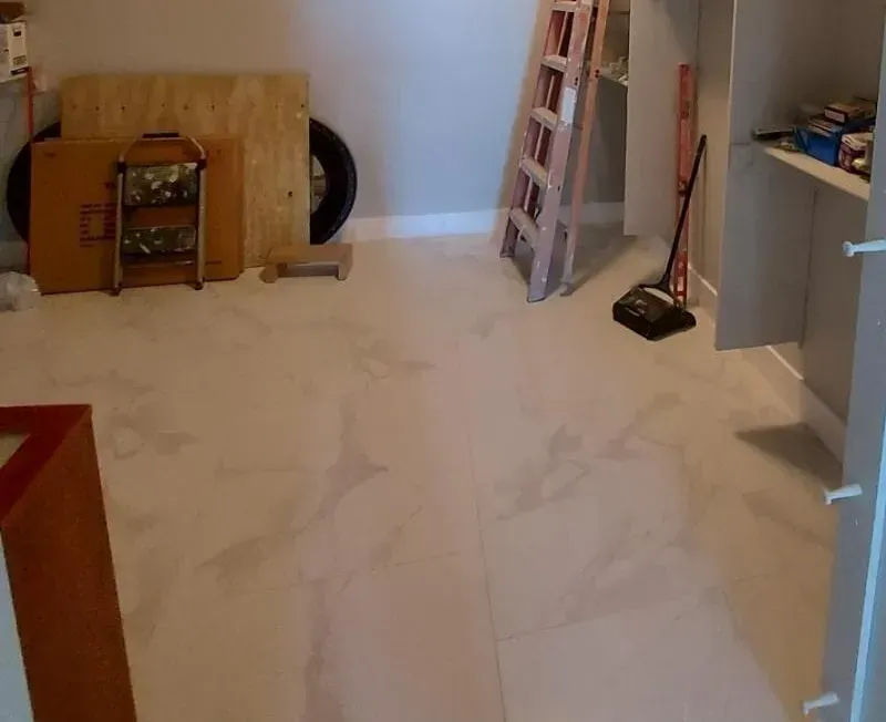 Room with white carpet, a ladder, shelving, and various items stored.