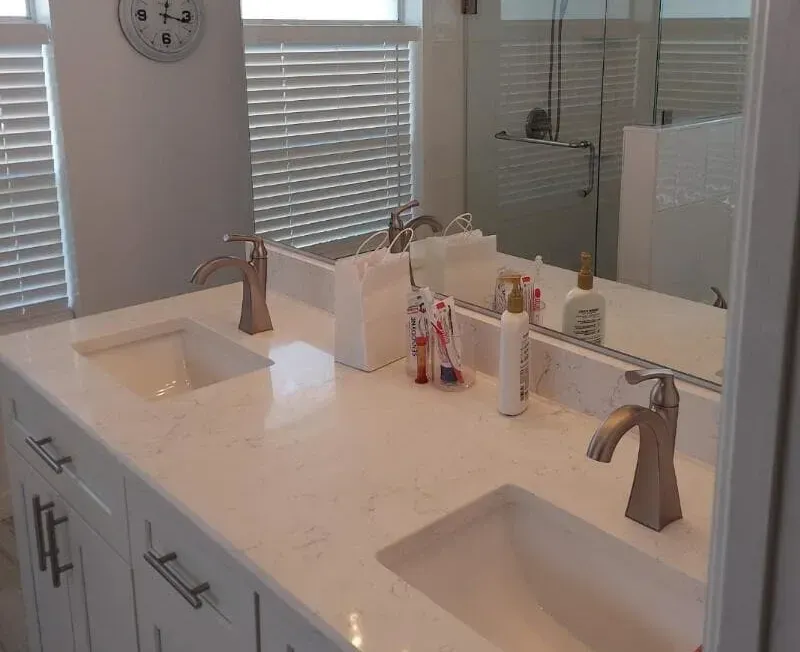 White bathroom vanity with two sinks, brushed nickel faucets, and a large mirror.
