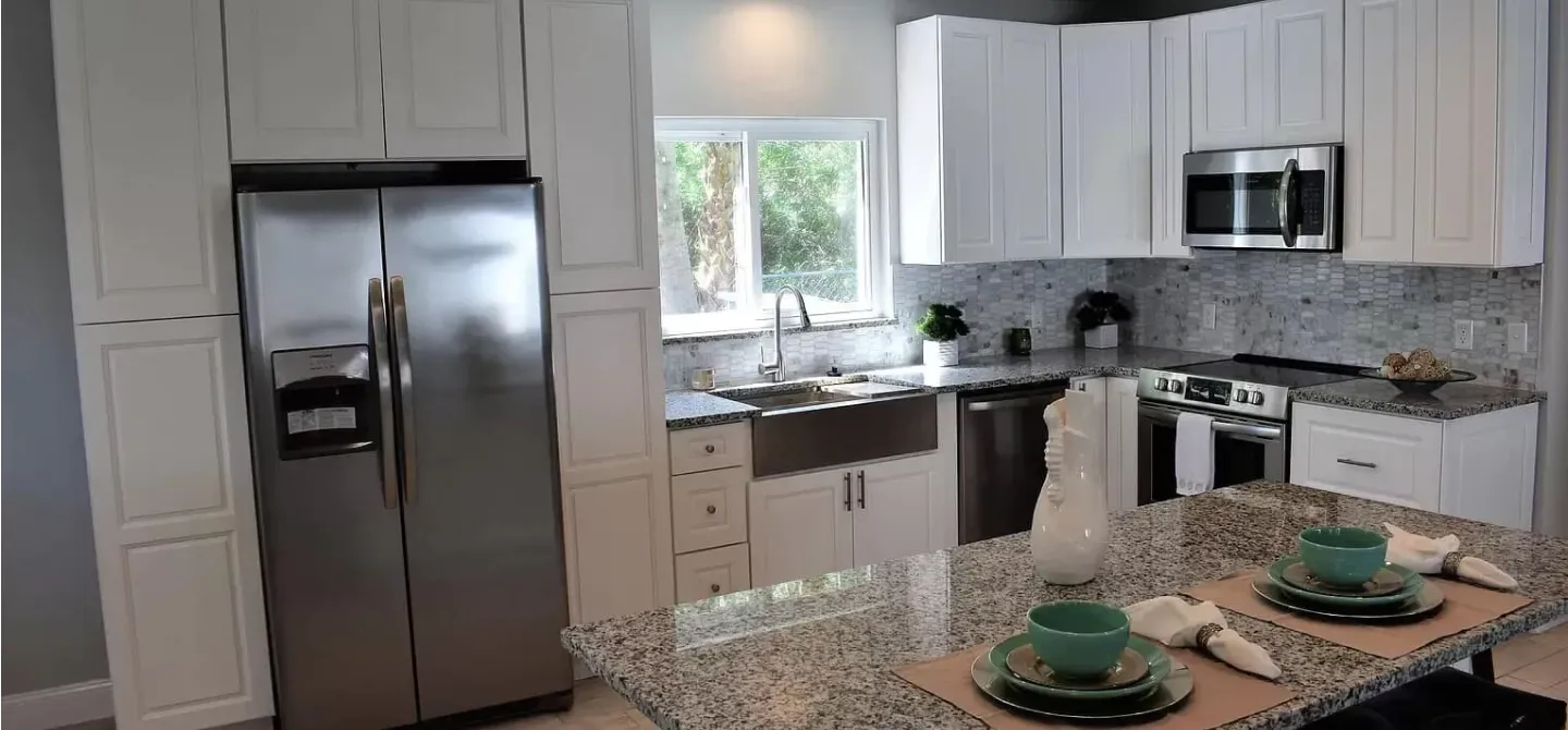 Modern kitchen with white cabinets, stainless steel appliances, and a granite island.