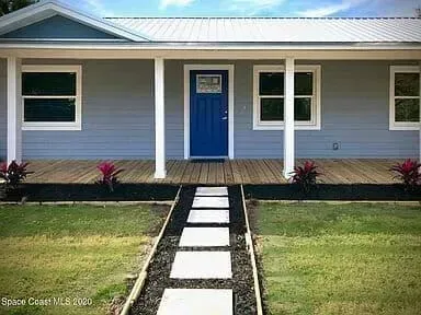 Blue house with white trim, porch, and walkway.