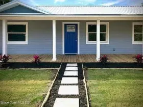 Blue house with a white porch, blue door, and a walkway of square stepping stones.