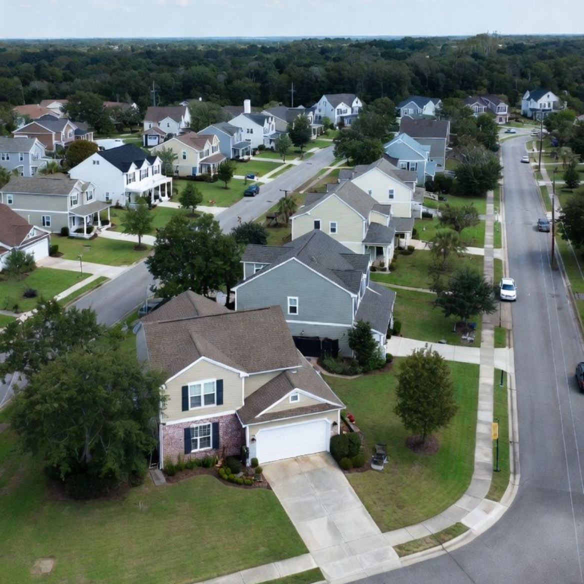 Aerial view of a suburban neighborhood with houses, streets, and trees under a cloudy sky.