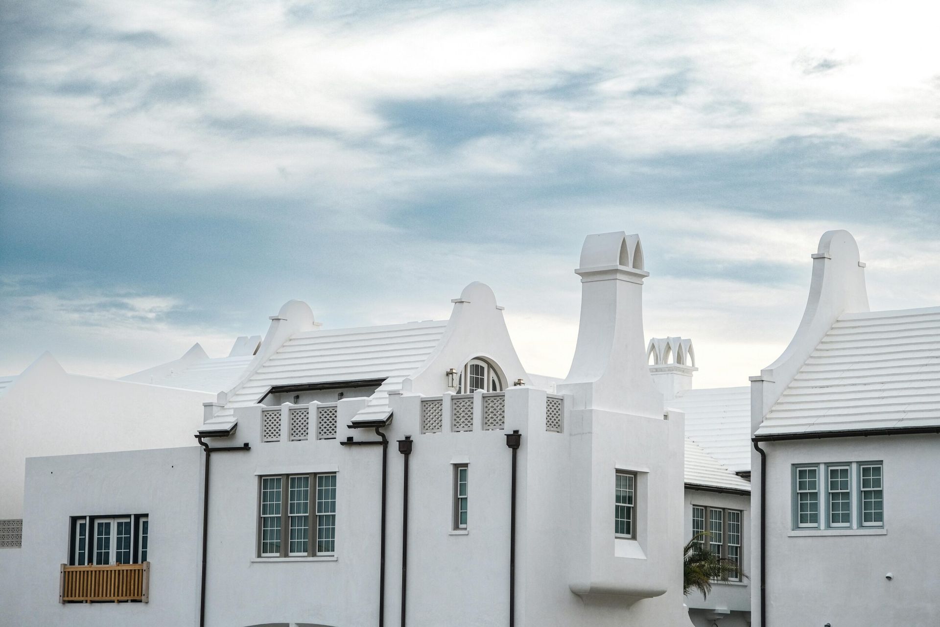 A row of white houses with a blue sky in the background.