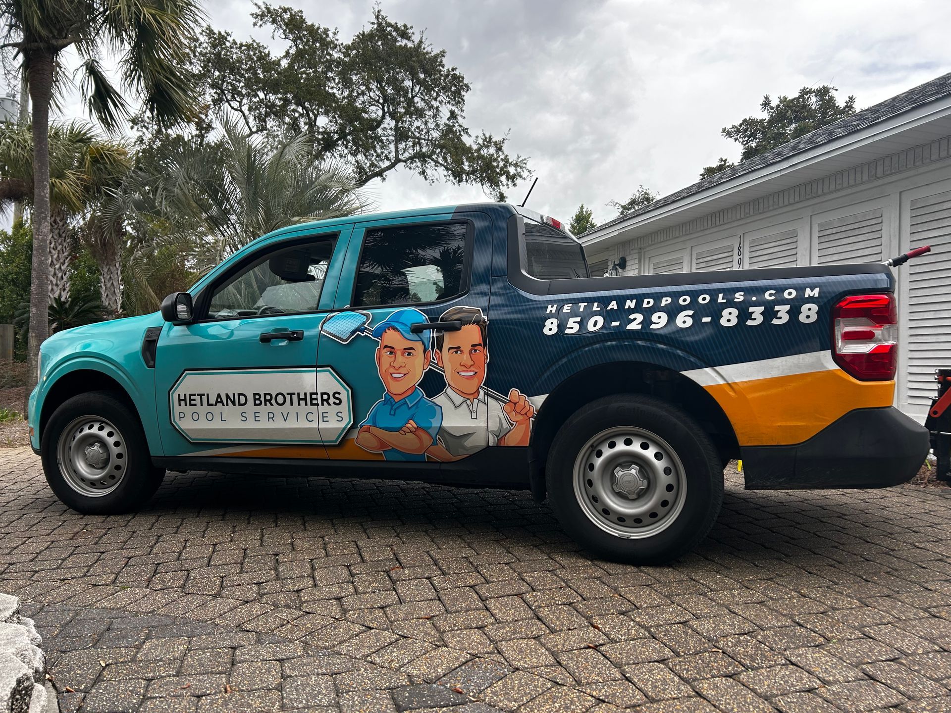 A blue and yellow truck is parked in front of a house.