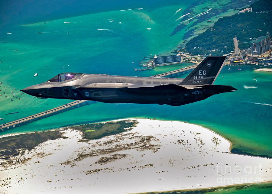 A fighter jet is flying over a body of water