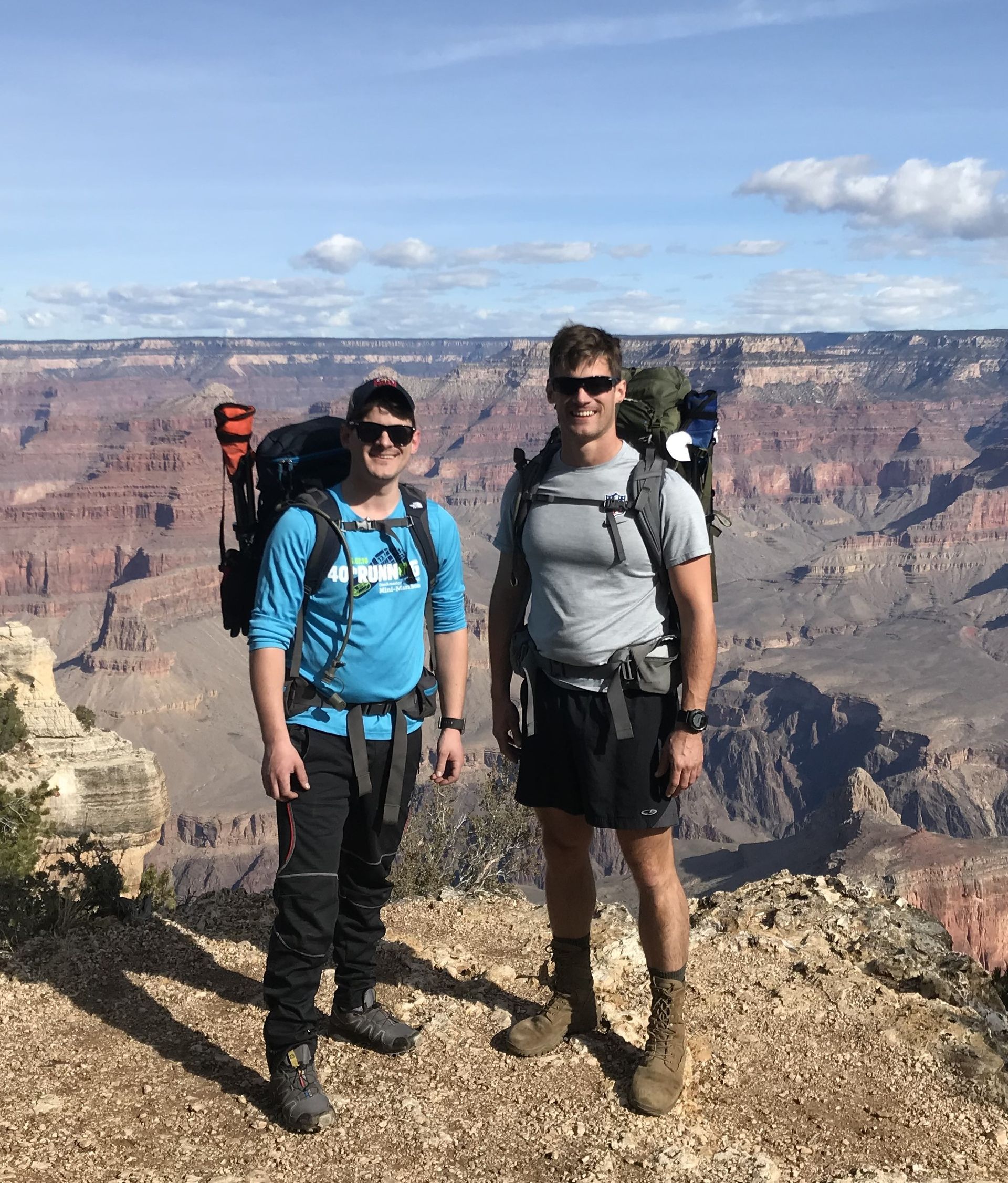 Two men with backpacks are standing on top of a mountain.
