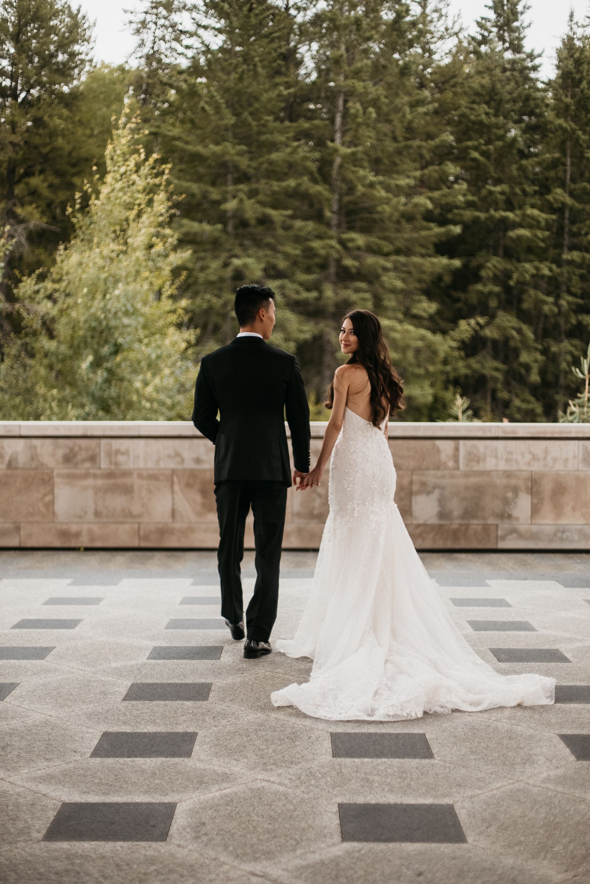 A bride and groom are holding hands while walking on a balcony.