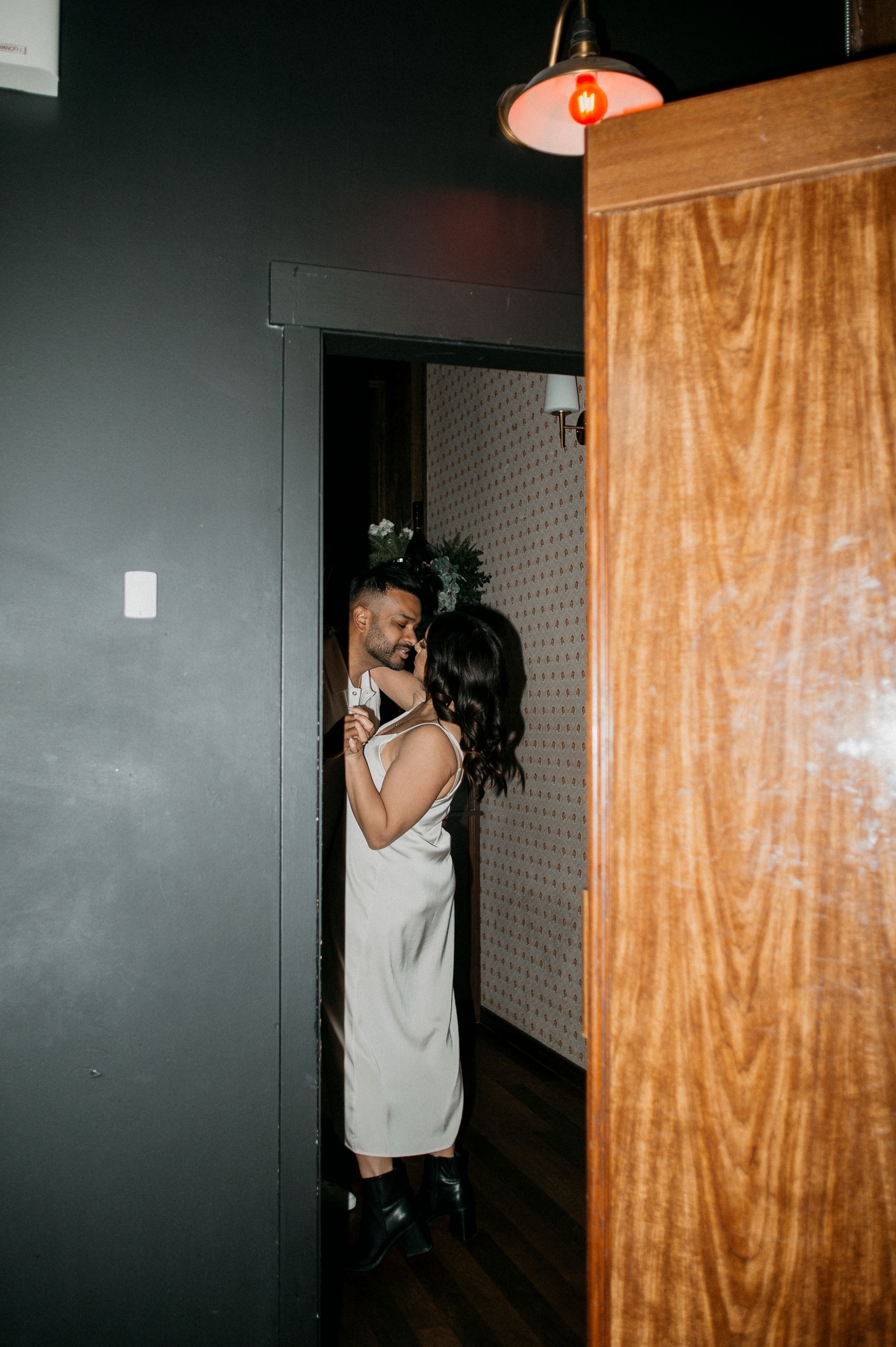 A bride and groom are hugging each other in a hallway.