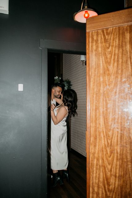 A bride and groom are hugging each other in a hallway.