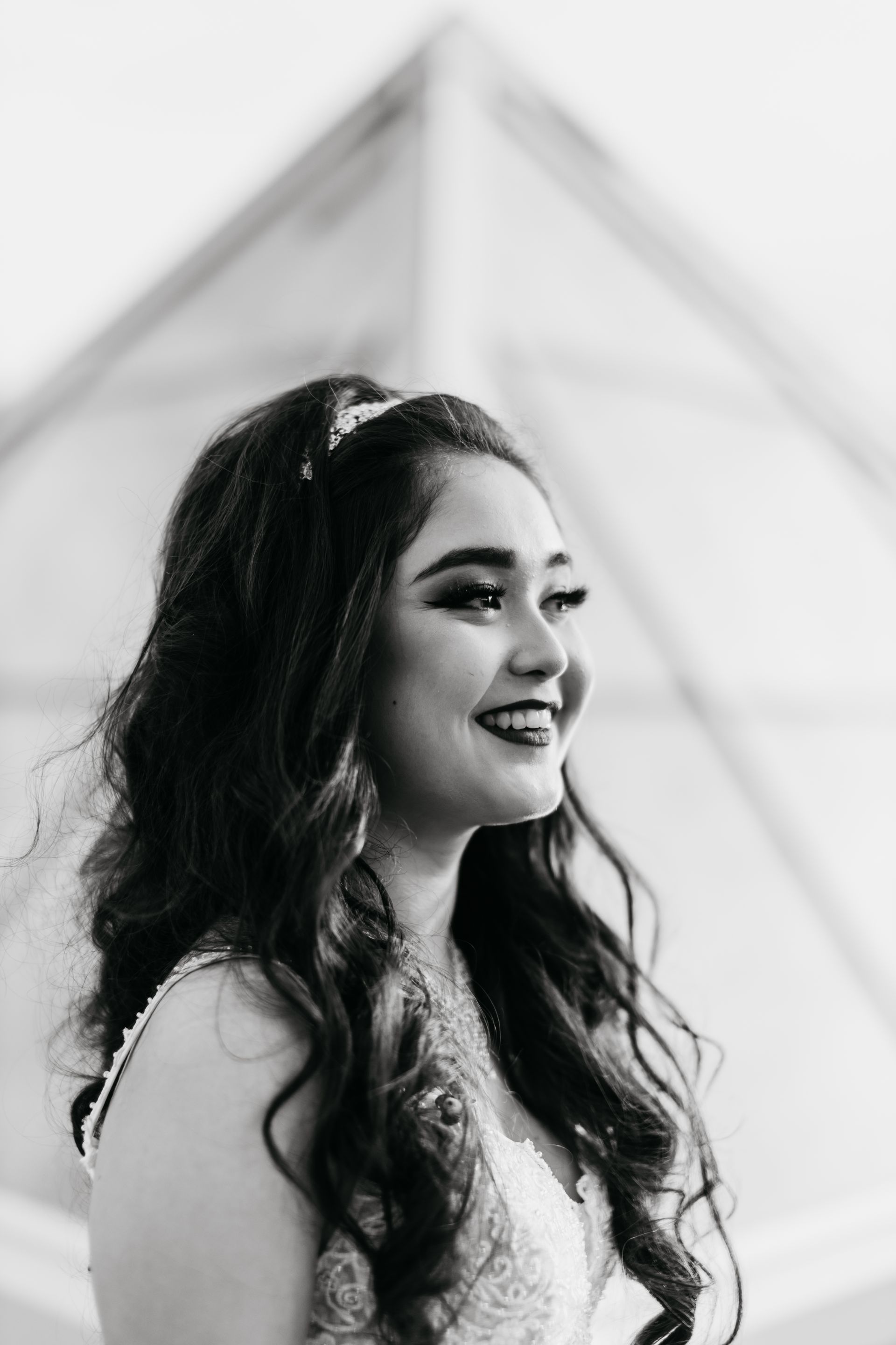 A woman in a wedding dress is smiling in a black and white photo.