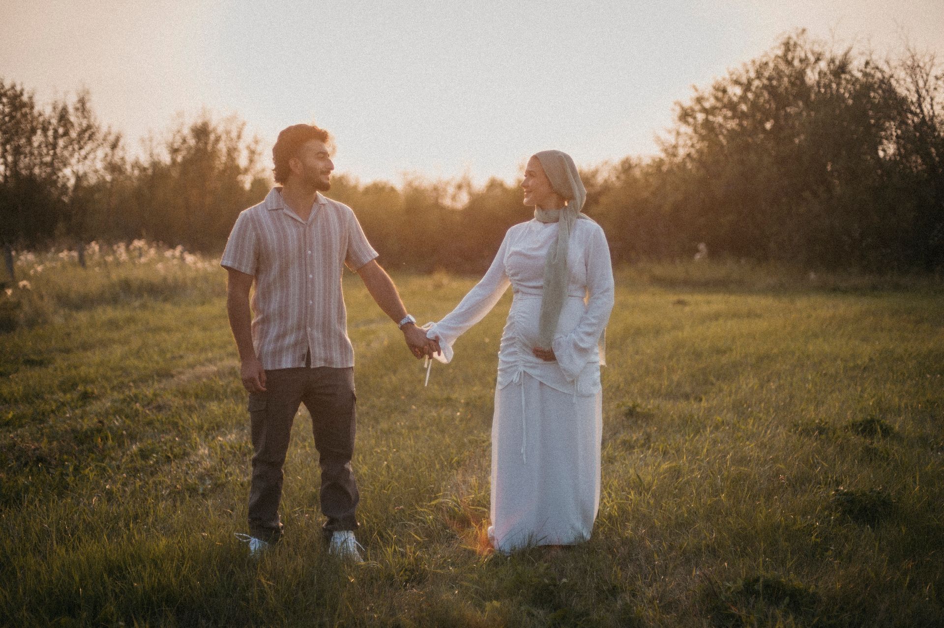 A man and a woman are holding hands in a field.