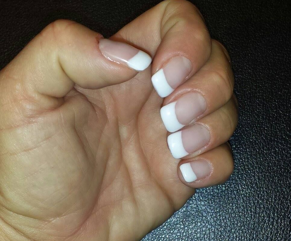 Hand with red and white nail art, including