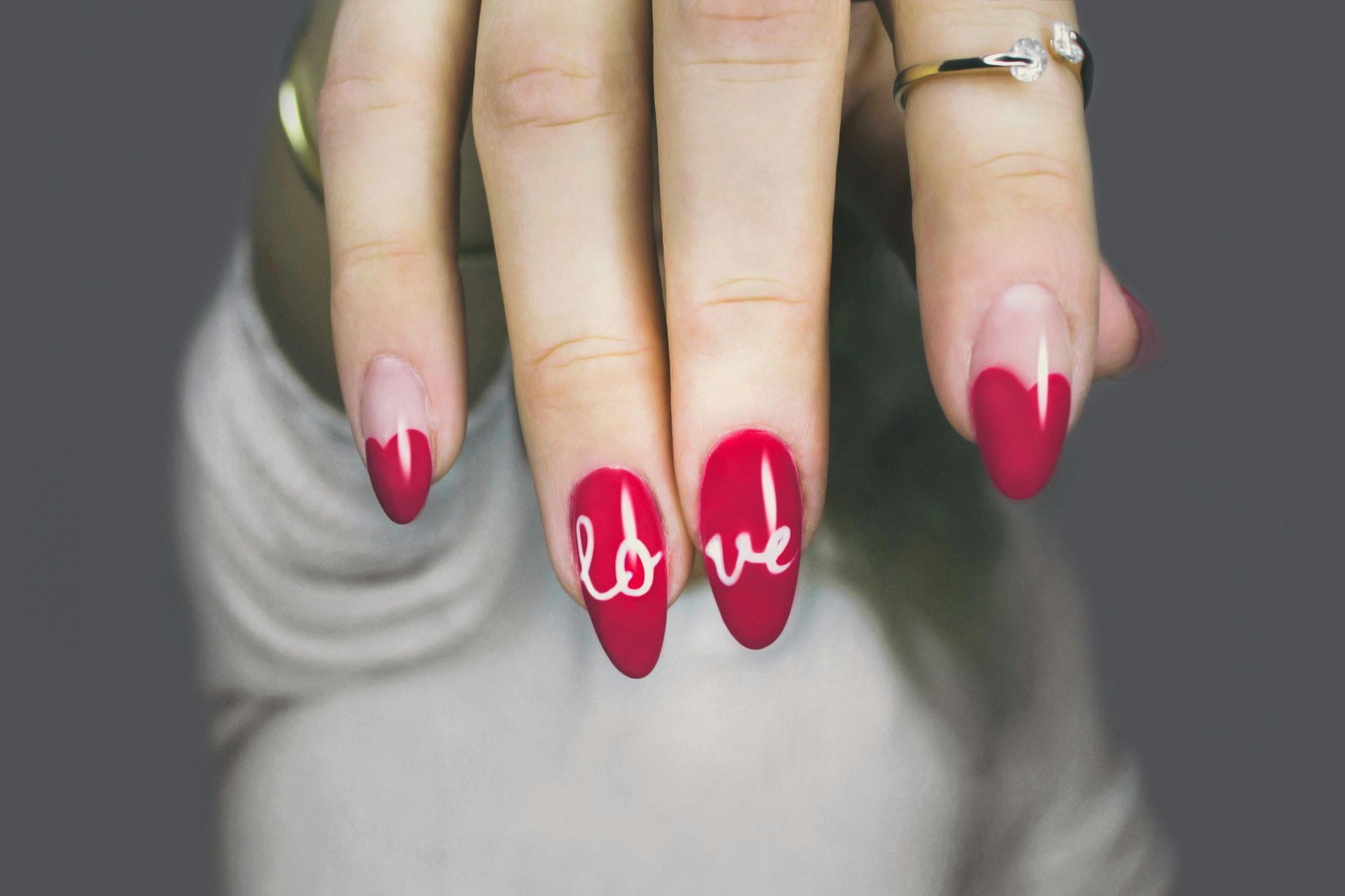 Hand with red and white nail art, including