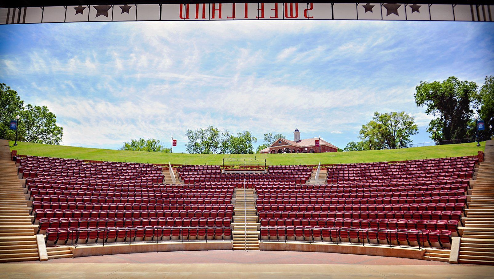 Burgundy Interkal AURA Slat Stadium Chairs with armrests with cupholders in the outdoor amphitheater at Boyd Sweetland.