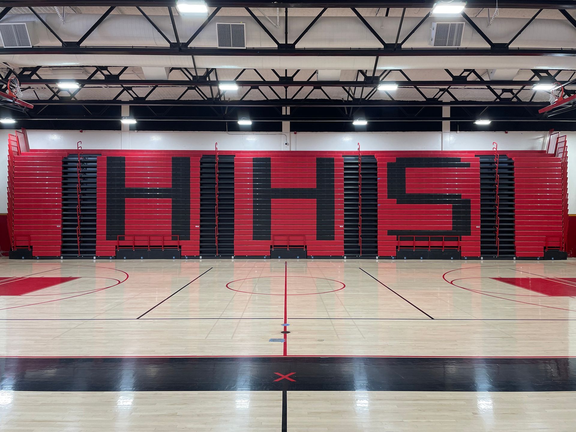 The telescopic bleacher system at Hemet High School in California, featuring custom red aisle rails and school initials.
