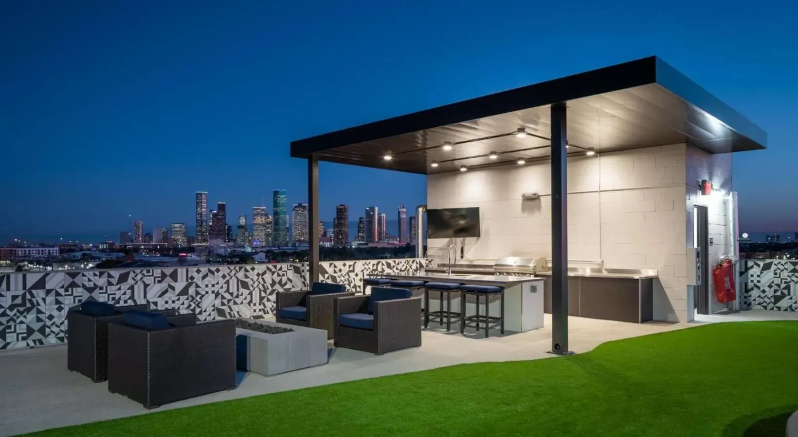 Rooftop grilling area and lounge with city skyline views at dusk.