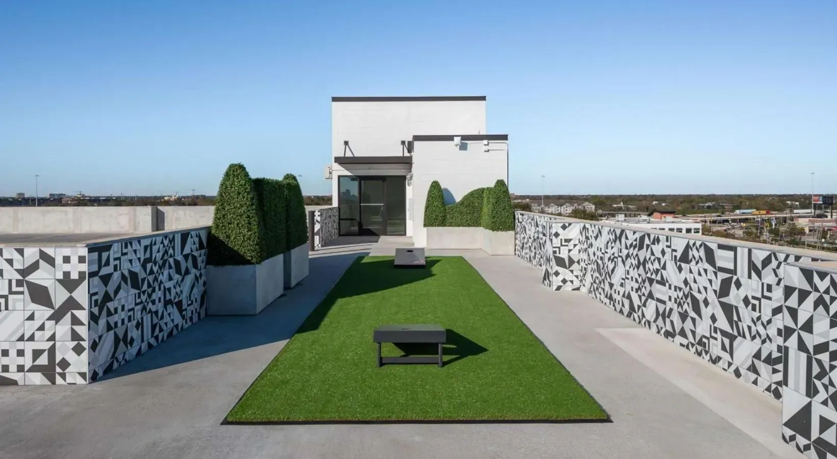 Rooftop patio with artificial turf, seating, and decorative walls.