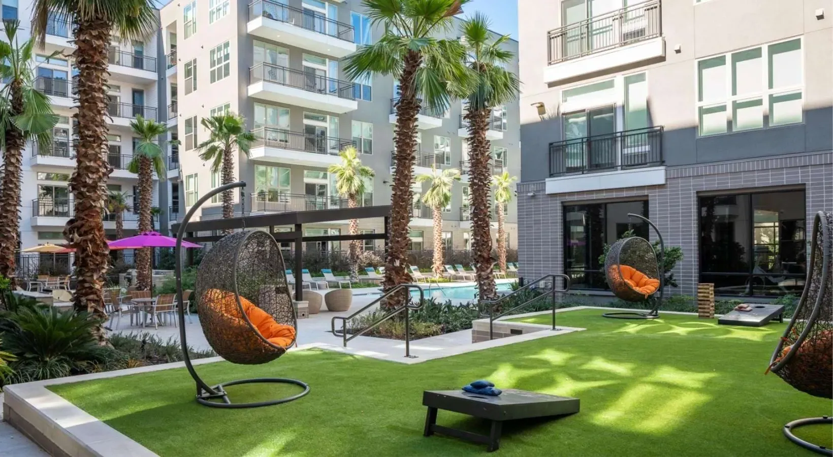 Chic outdoor lounge area with hanging chairs and a pool in the background