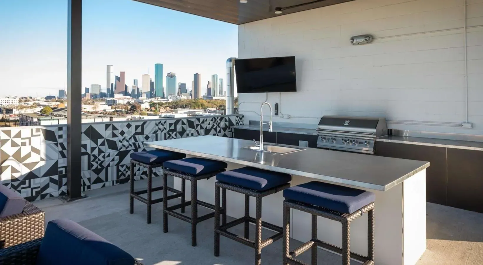 Rooftop outdoor kitchen with bar seating and city skyline view