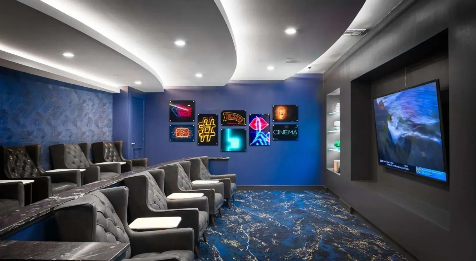 Luxury theater room with plush seating and neon cinema signs.