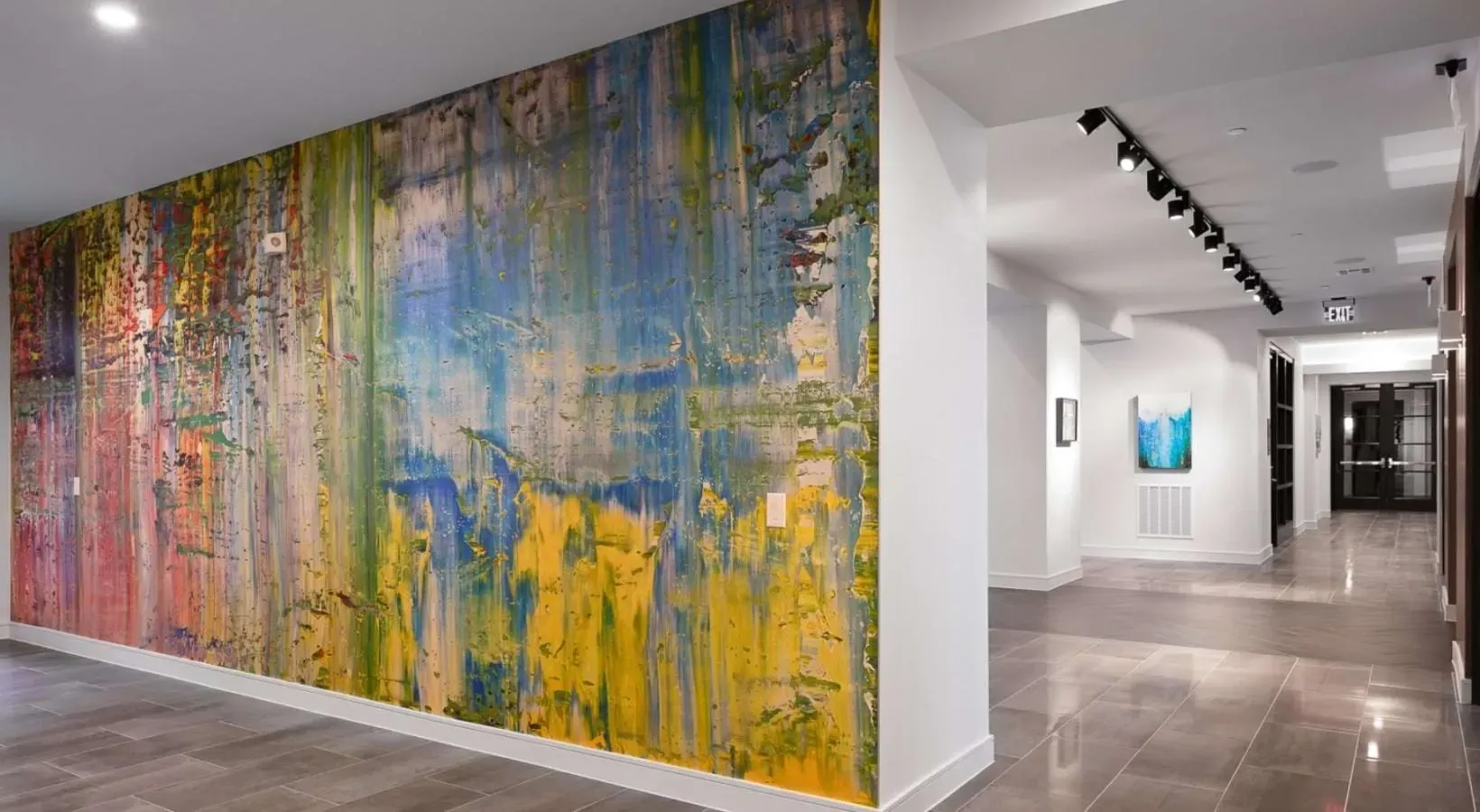 Hallway with abstract art mural and track lighting.