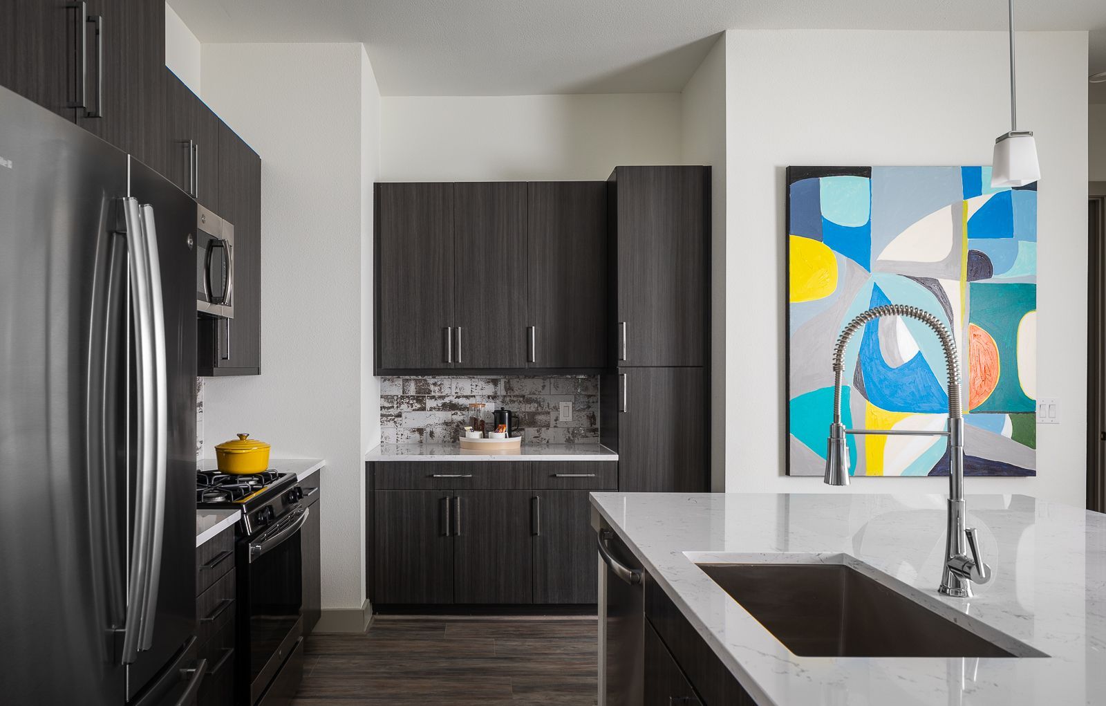 Modern kitchen with stainless steel appliances and dark wood cabinets.