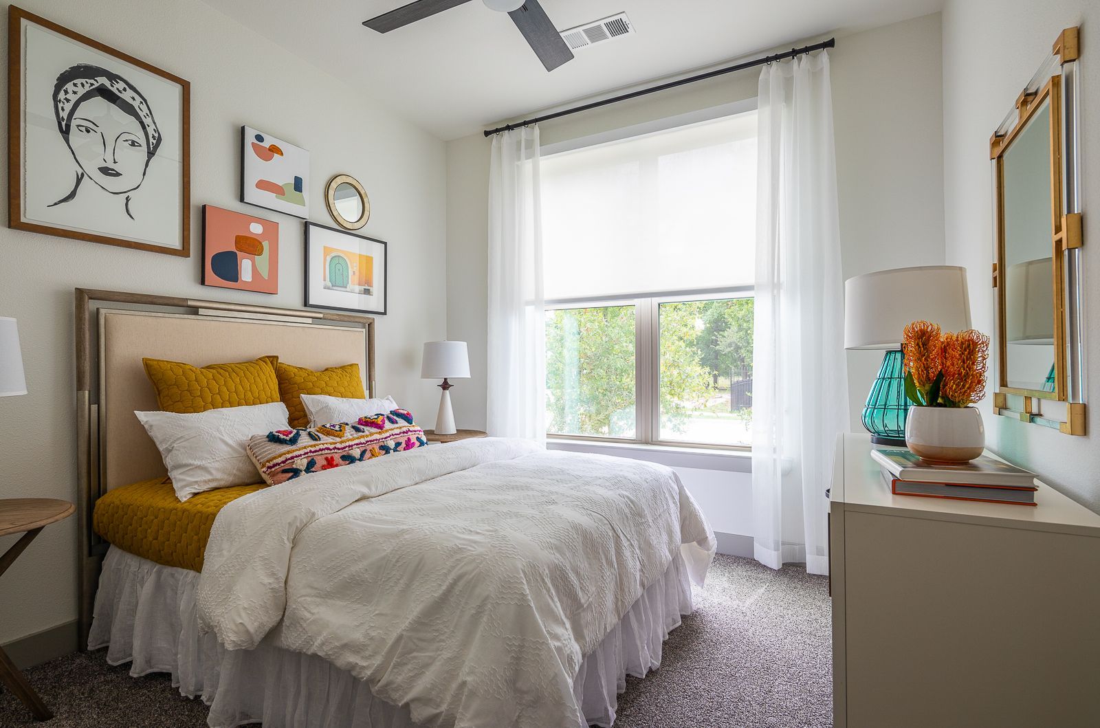 Cozy bedroom with a queen-size bed, colorful accent pillows, and artwork on the wall.
