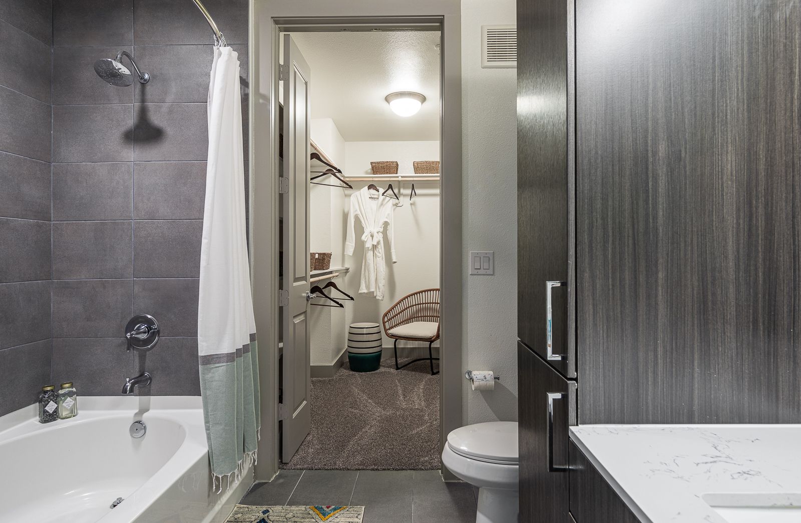 Modern bathroom with walk-in closet, featuring a soaking tub, shower, and vanity.