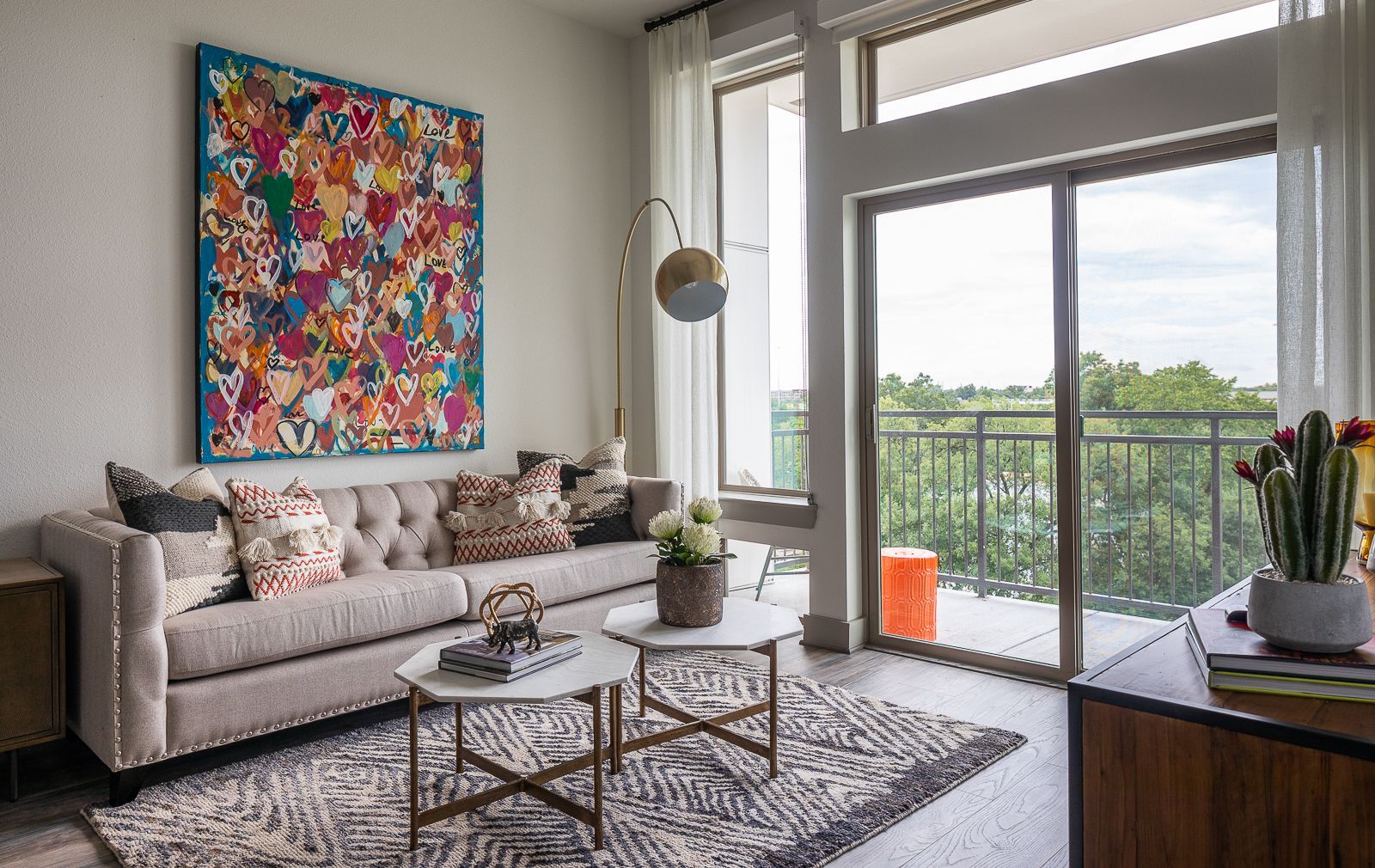 Modern living room with plush sofa, abstract art, and balcony view.