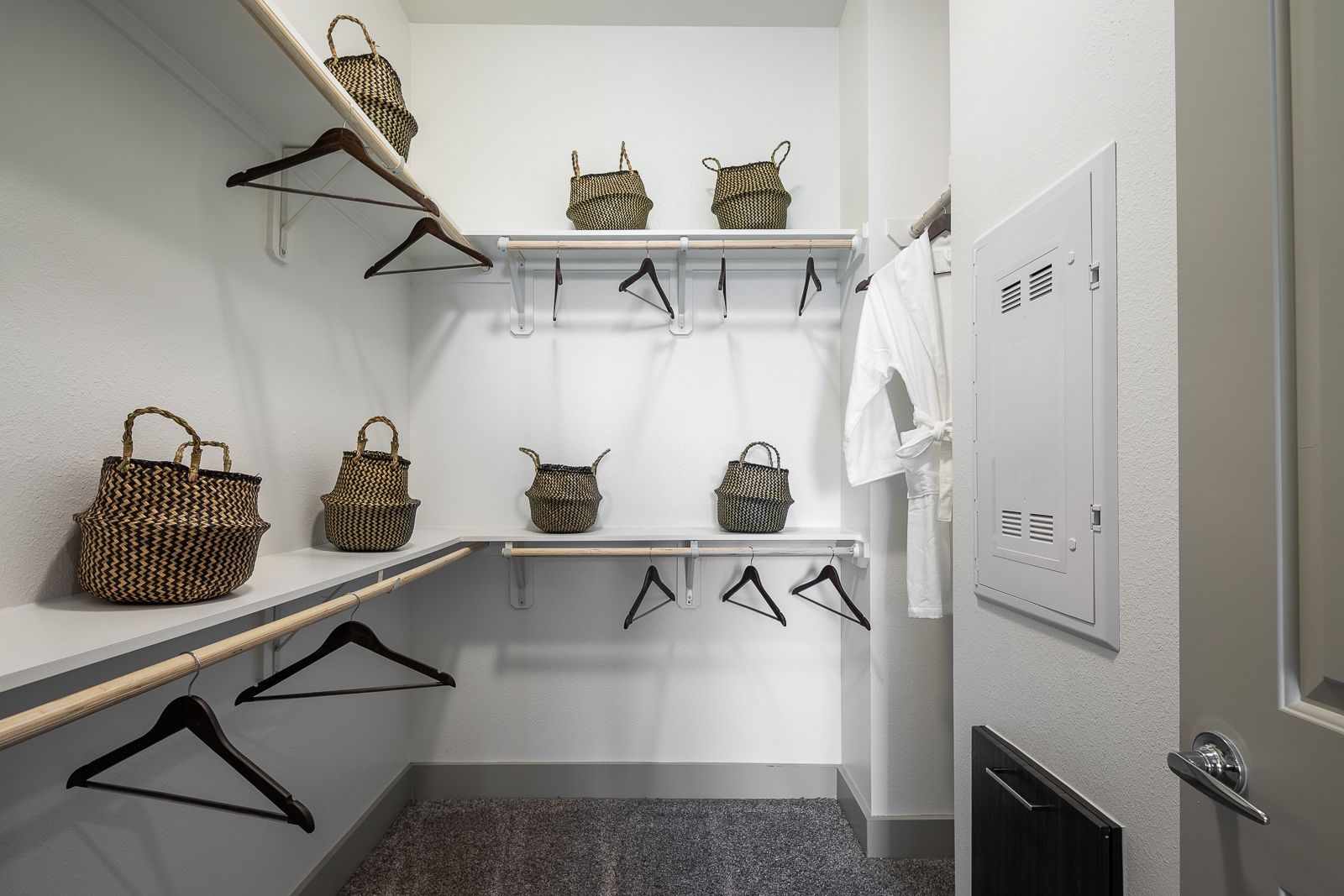 Walk-in closet with shelves, hanging rods, and decorative baskets.
