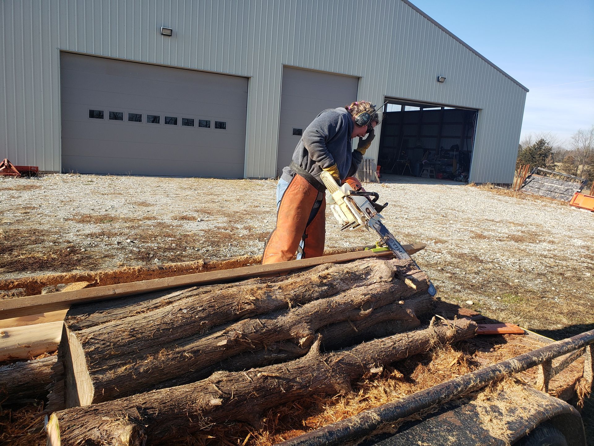 snellen wood products employee using chainsaw on cedar logs
