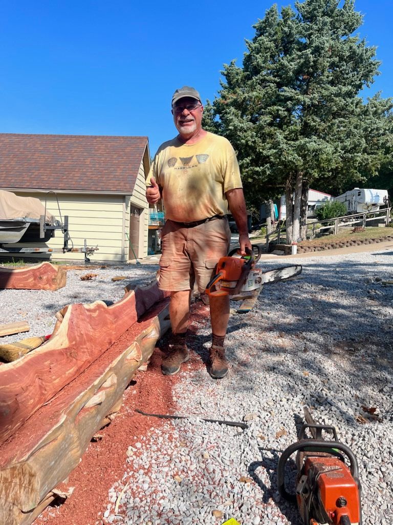 Snellen Wood Products Employee standing next to Cedar Log with a Chainsaw